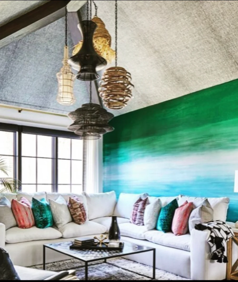 Ombré green-to-white LUCiTE wall panel behind a sectional, with woven pendant lights