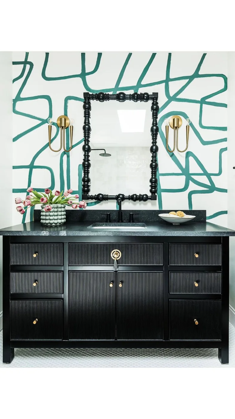 Hand-painted green abstract line mural behind a black vanity with brass fixtures