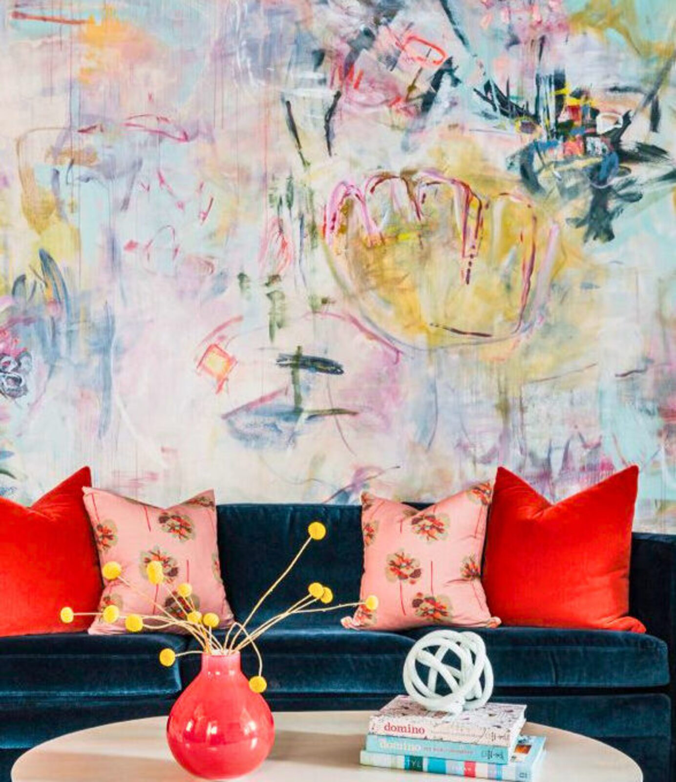 Sweeping pastel wall mural above a navy velvet sofa